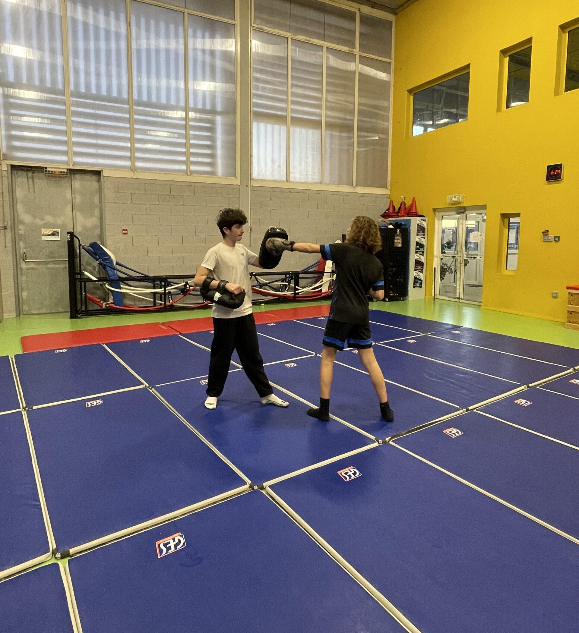 2 adolescents de 15 ans en train de s'entrainer en kung fu sanda sur une technique de coup de poing