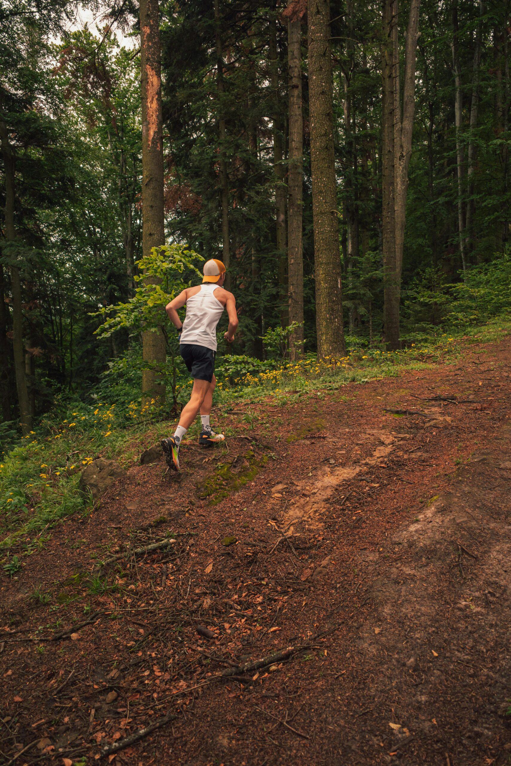Athlete running on a forest path, showcasing outdoor fitness and adventure in a lush green summer setting.